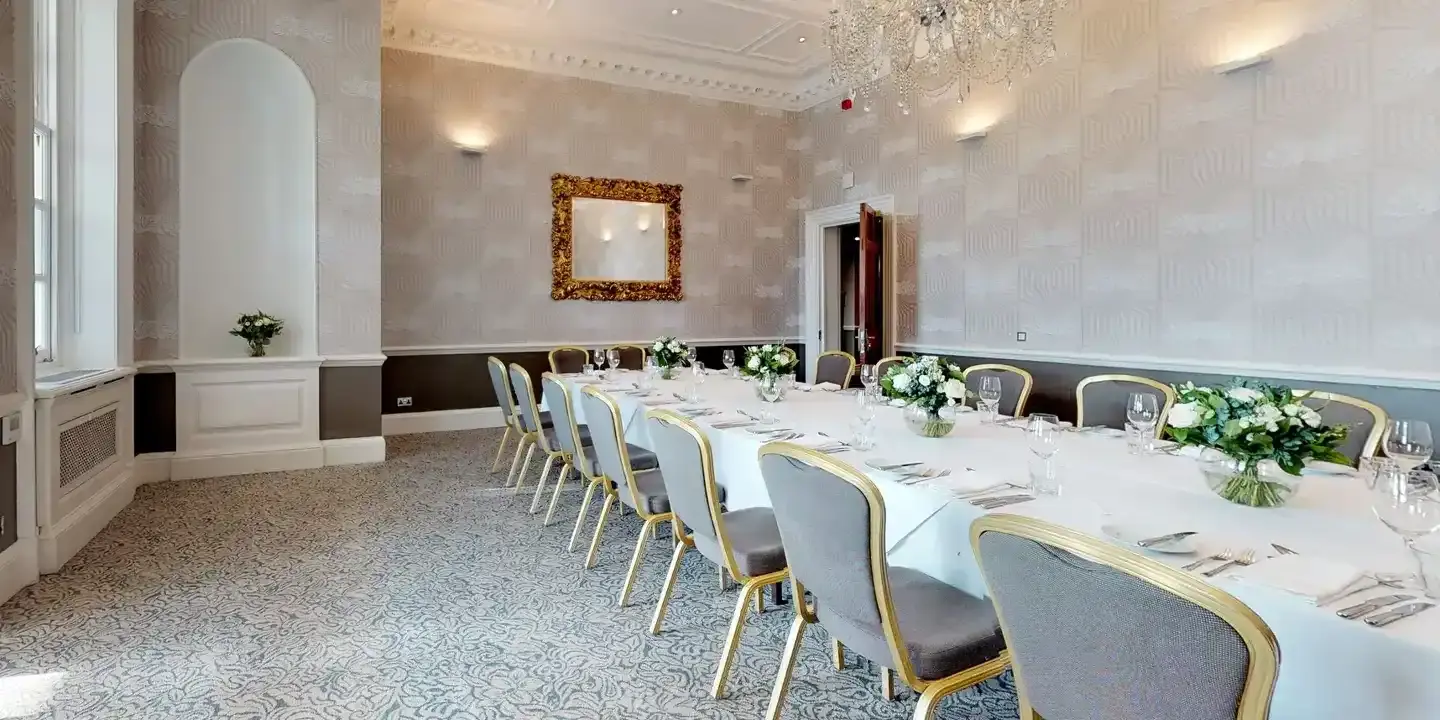 A dining room featuring a lengthy table adorned with an elegant chandelier.