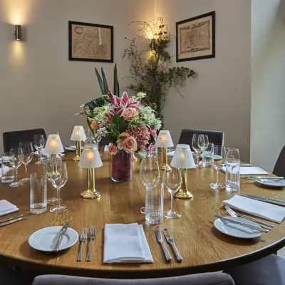 Wooden table adorned with wine glasses and silverware.
