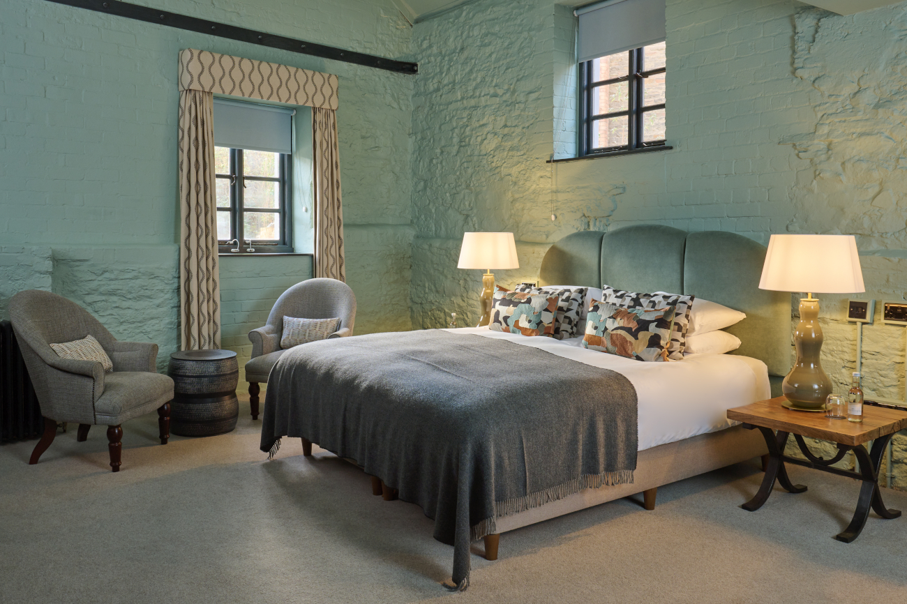 Spacious bedroom featuring a king-sized bed and an elegant chair.