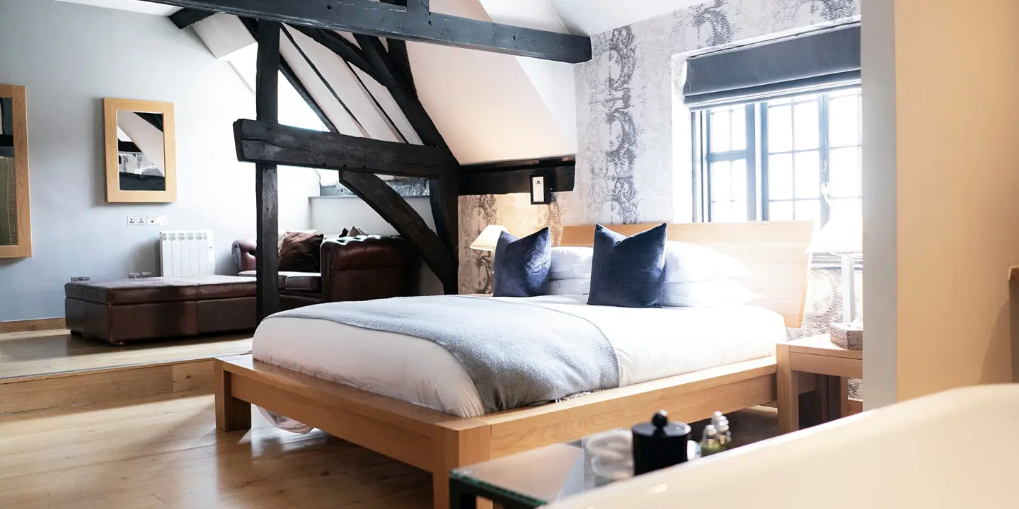 Bed in front of a window with dark wooden beams surrounding 