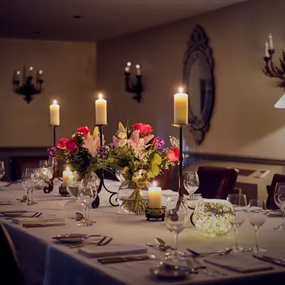 Table elegantly set for a formal dinner, adorned with candles and flowers.