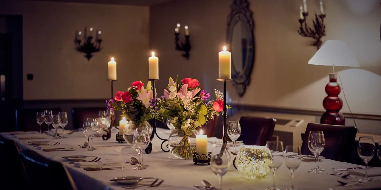 Table elegantly set for a formal dinner, adorned with candles and flowers.