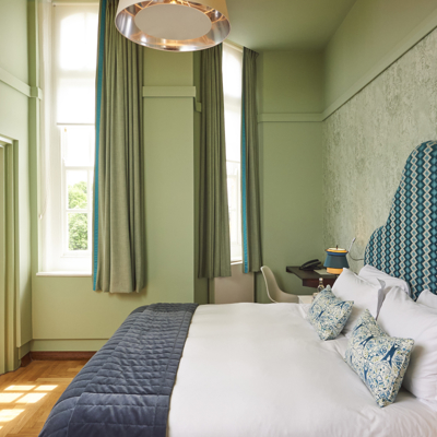 Spacious bedroom featuring a generously-sized bed with an elegant blue headboard.