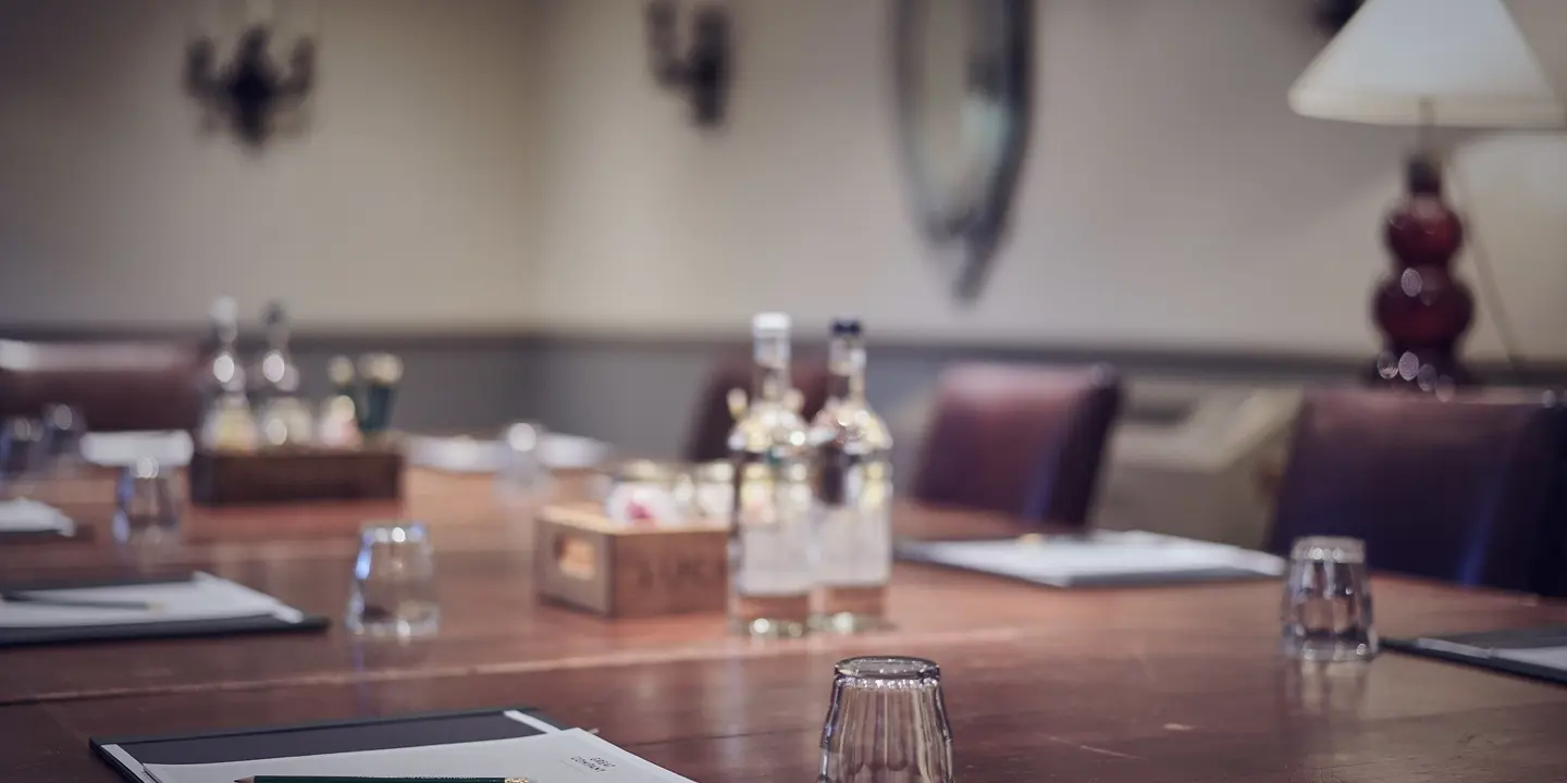 A wooden table adorned with glasses and bottles of water.