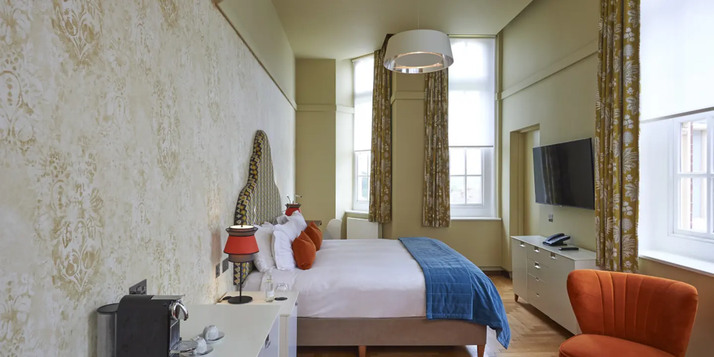 An elegantly furnished hotel room featuring a comfortable bed, spacious desk, and cozy chair.