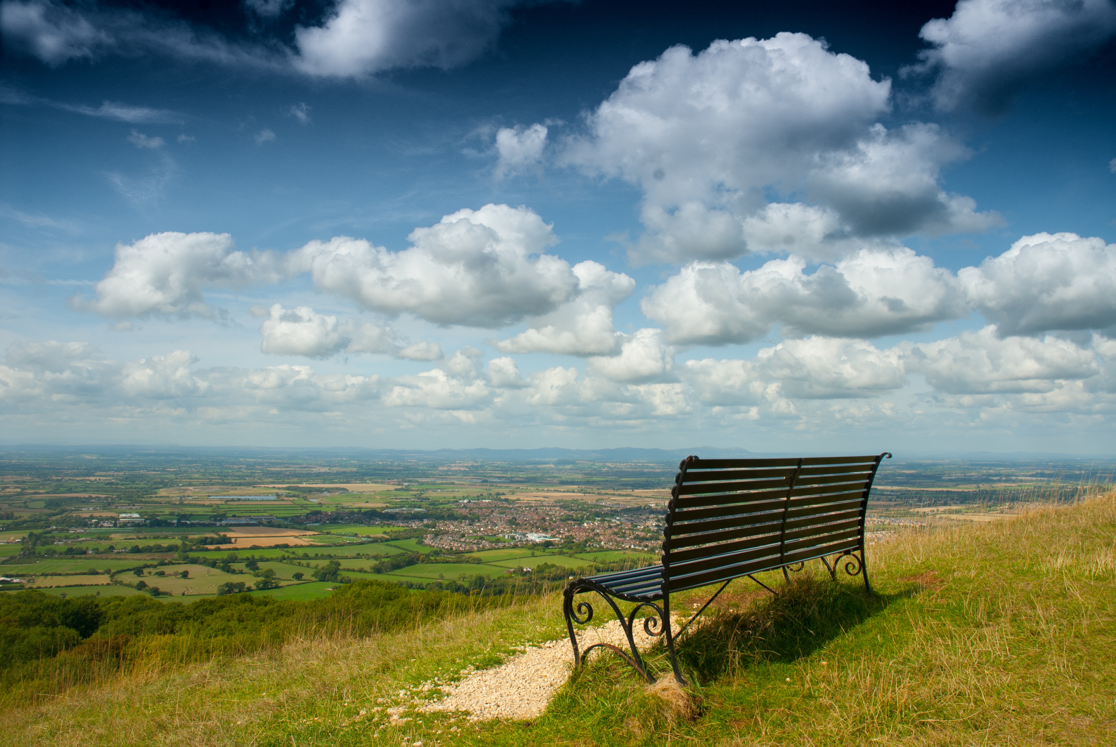 A wooden bench resting atop a verdant hillside.