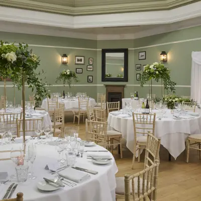 Round table adorned with white cloth, champagne glasses and flower arrangements.