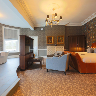 Spacious bedroom featuring a king-sized bed and an elegant bathtub.