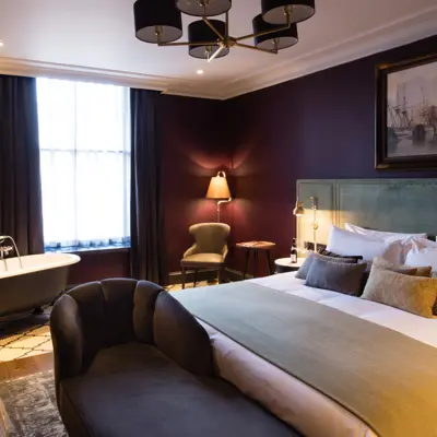 Spacious bedroom featuring a king-sized bed and an elegant bathtub.