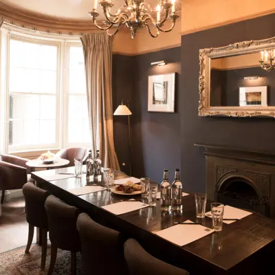 Meeting room featuring a dark long table and chairs set with glasses and bottled water. 