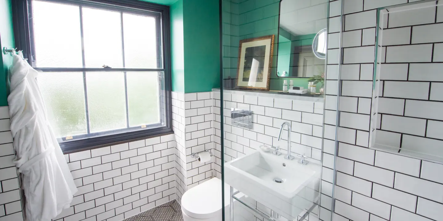 A bathroom featuring a toilet, sink, and window.