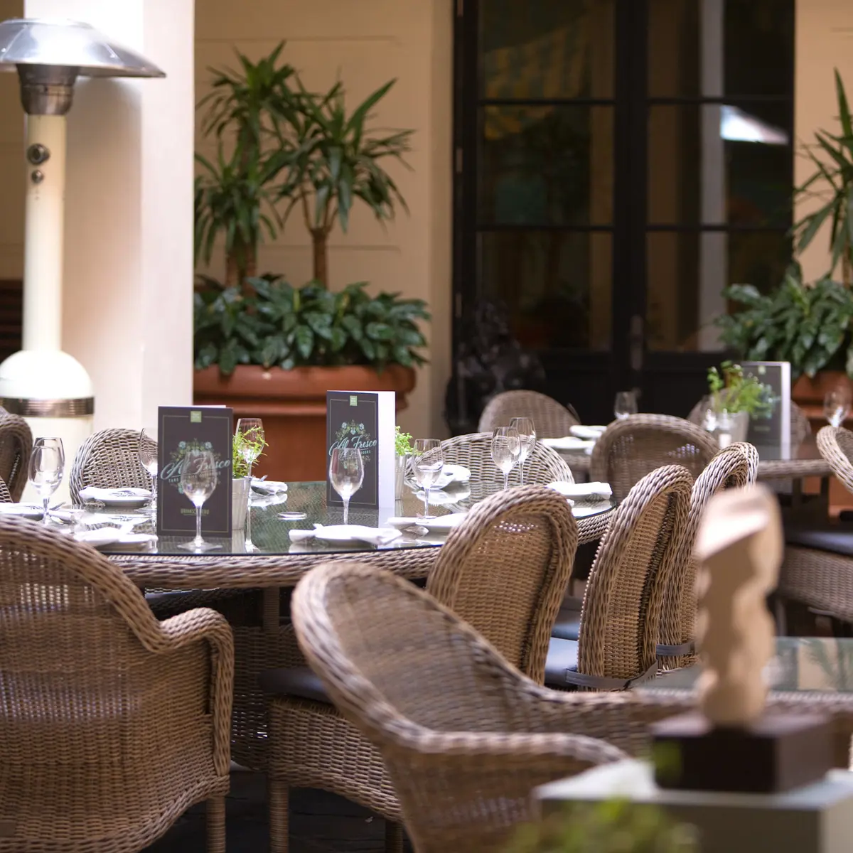 Straw dining seats surrounding dining tables which are place outside of the restaurant