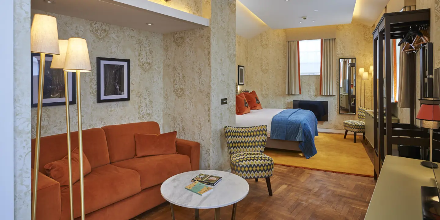 An elegantly furnished hotel room featuring a comfortable bed, sofa and a functional desk.