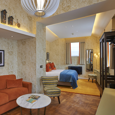 An elegantly furnished hotel room featuring a comfortable bed, sofa and a functional desk.