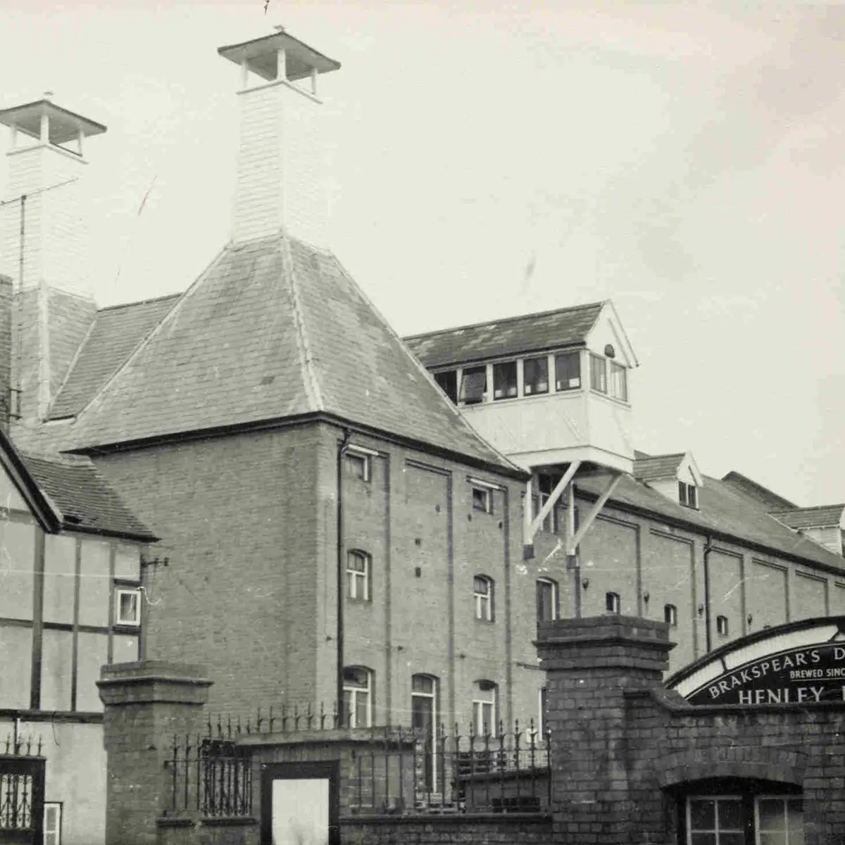 Black‑and‑white historic photograph of the Brakspear Brewery building, taken from the left‑side perspective, showing the front façade and a partial view of the Brakspear draught sign.