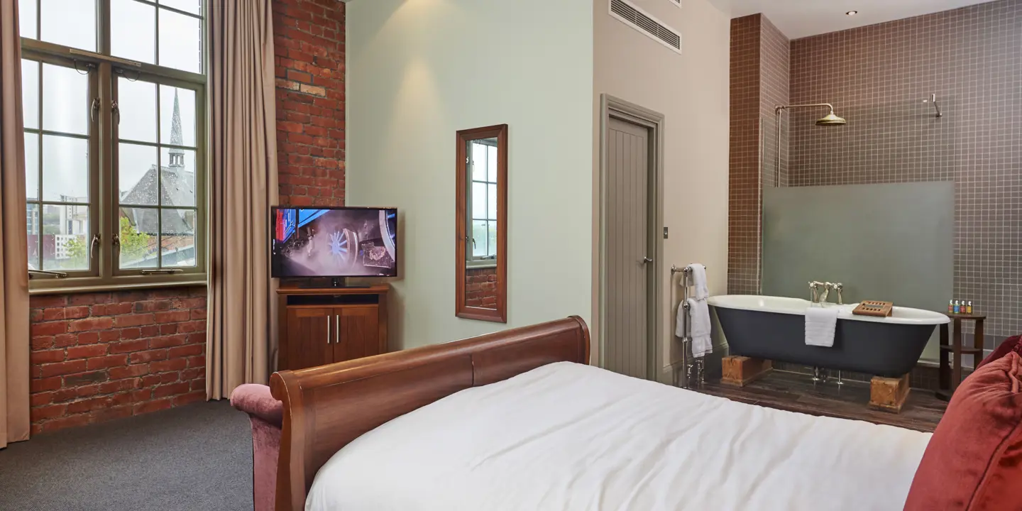 Bedroom featuring a comfortable bed, television, and bathtub.