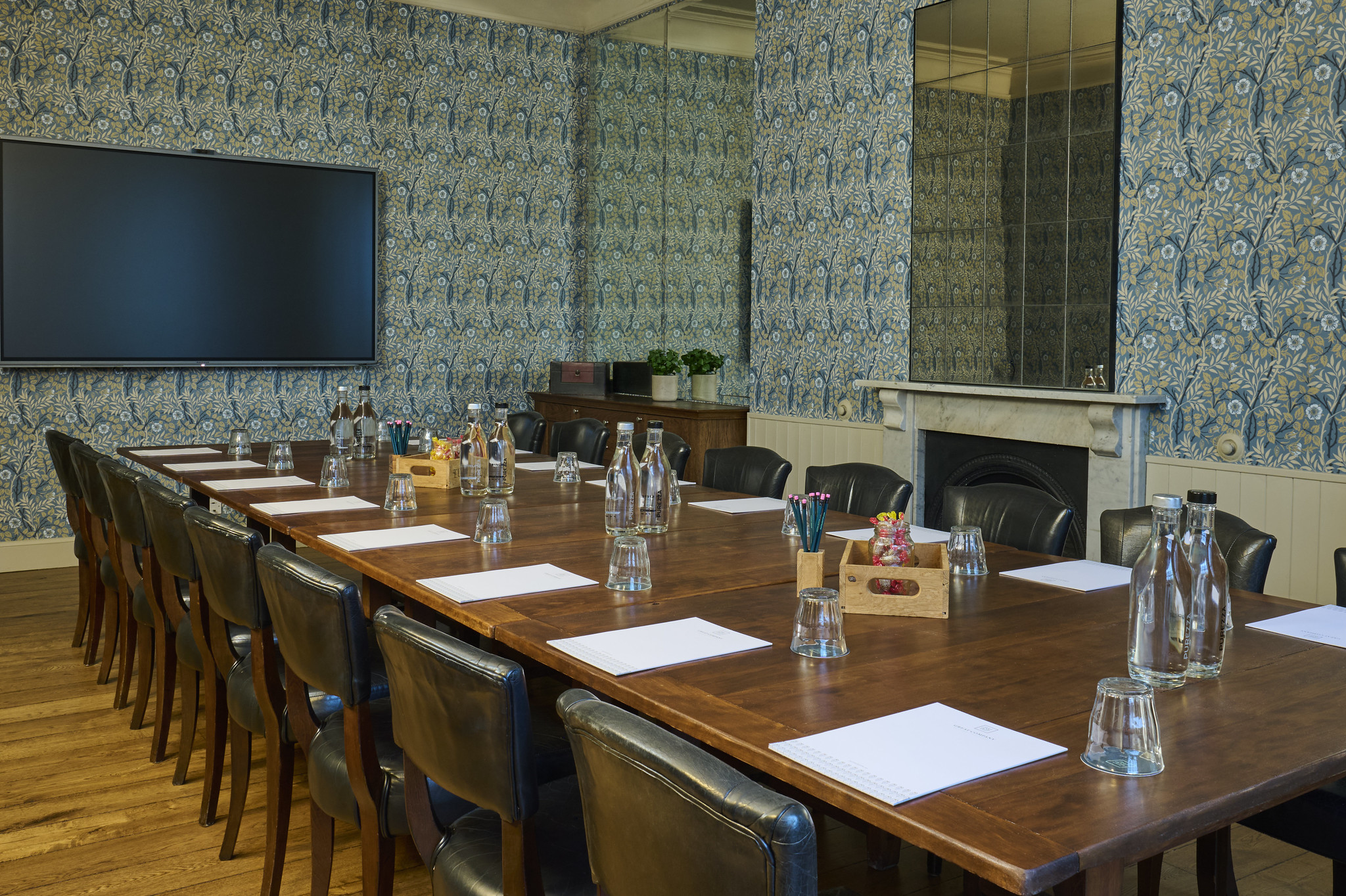 An elegantly furnished room featuring black leather chairs arranged around a cozy fireplace.