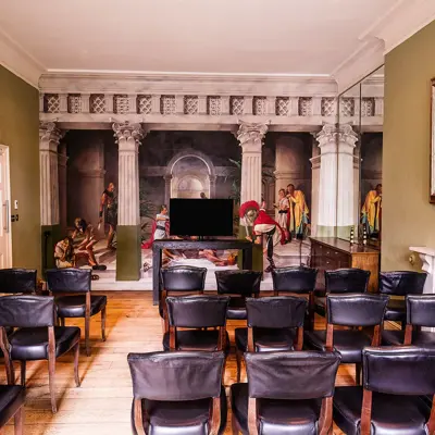 An elegantly furnished room featuring black leather chairs arranged around a cozy fireplace.