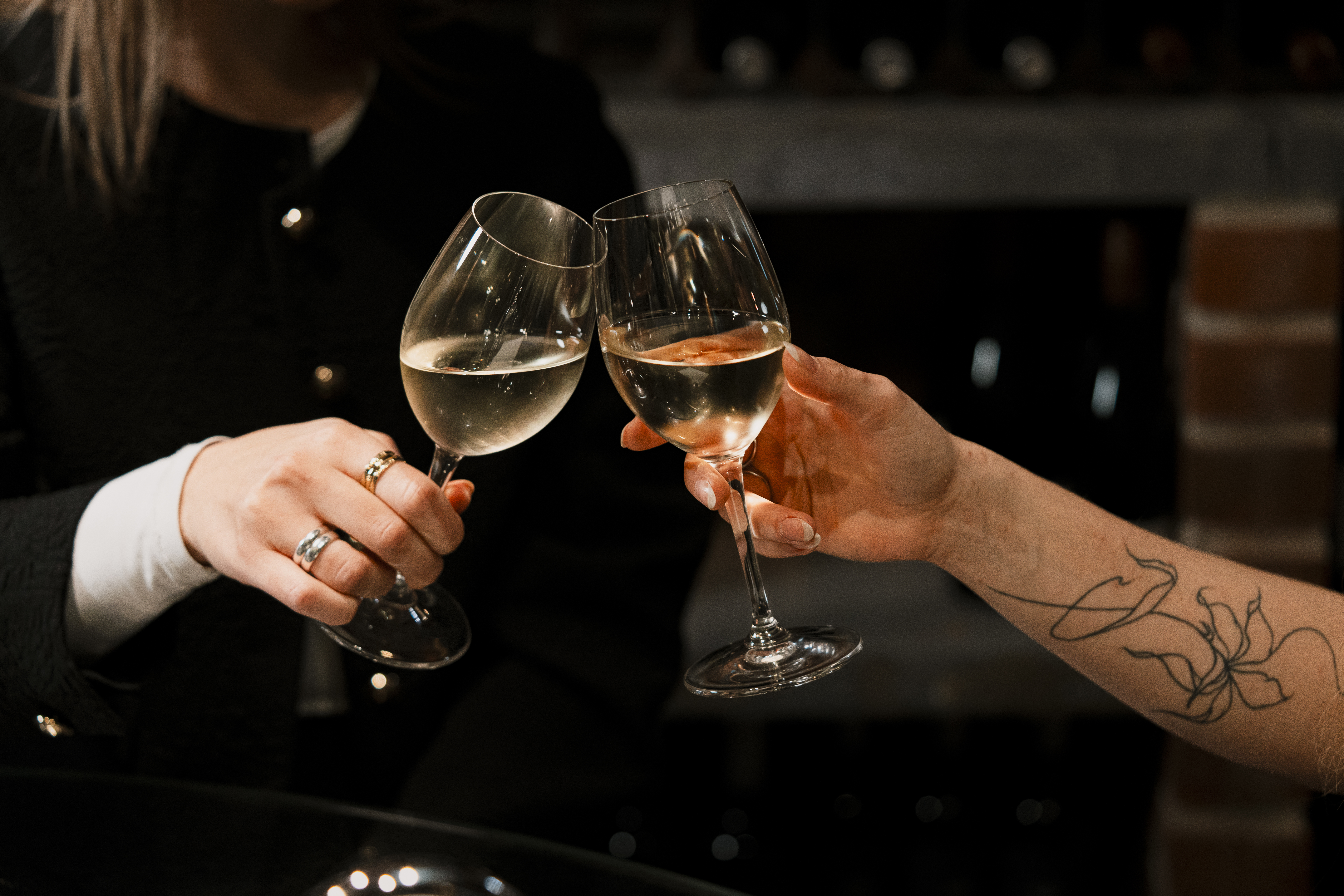 Two people drinking white wine clinking glasses