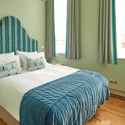 A bed adorned with a stylish blue and white comforter, accompanied by matching pillows.