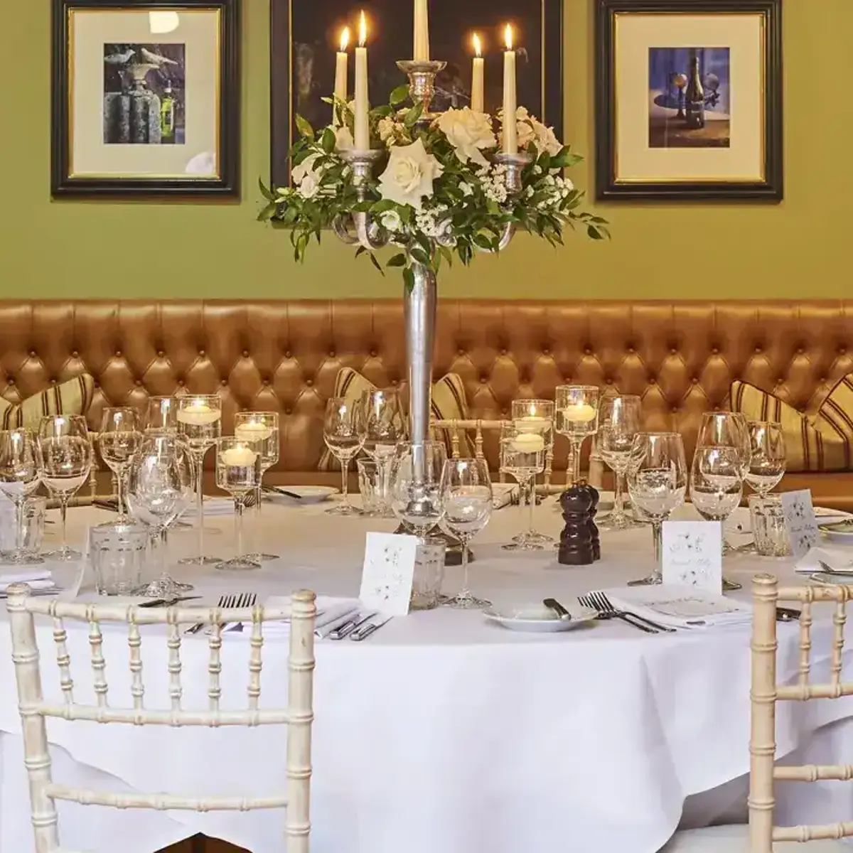 Dining room featuring a spacious banquet table with a white table cloth, surrounded by elegant chairs.