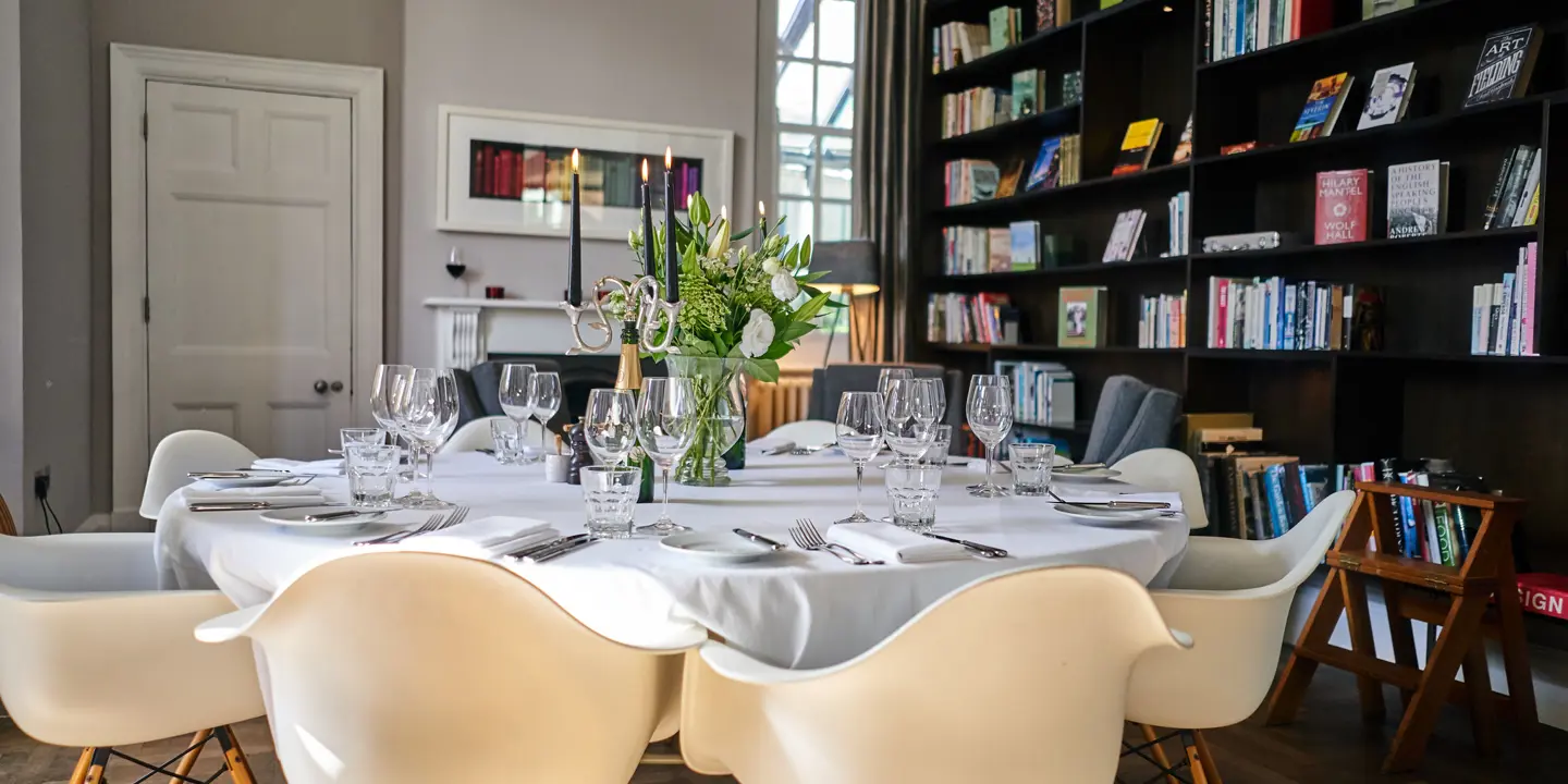 A dining table set with white chairs and a vase of flowers.