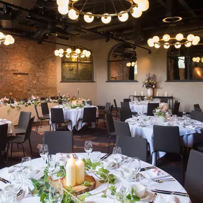 A dining room set with tables and chairs arranged for a dinner gathering.