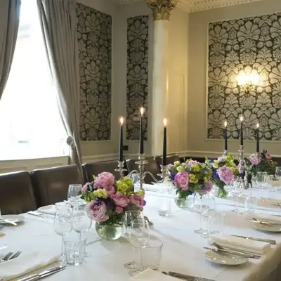 Table elegantly set for a formal dinner, adorned with candles and flowers.