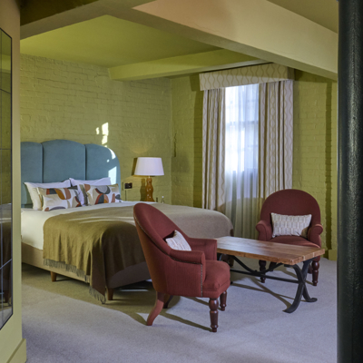 An elegantly furnished hotel room featuring a comfortable bed and a functional desk.