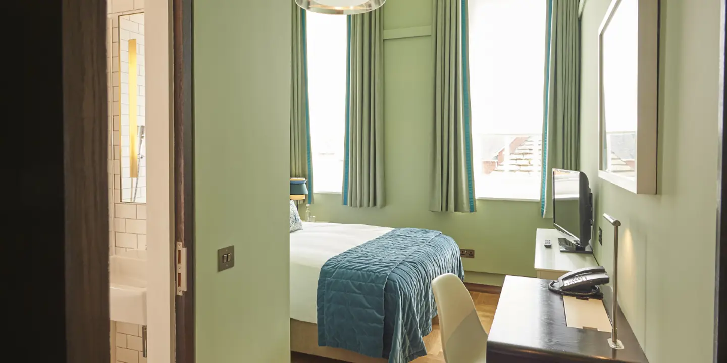 An elegantly furnished bedroom featuring a comfortable bed, a sleek desk, and a picturesque window.