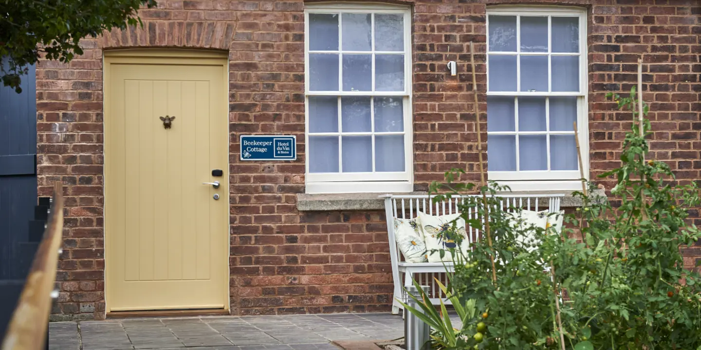 A white bench positioned in front of a yellow door.