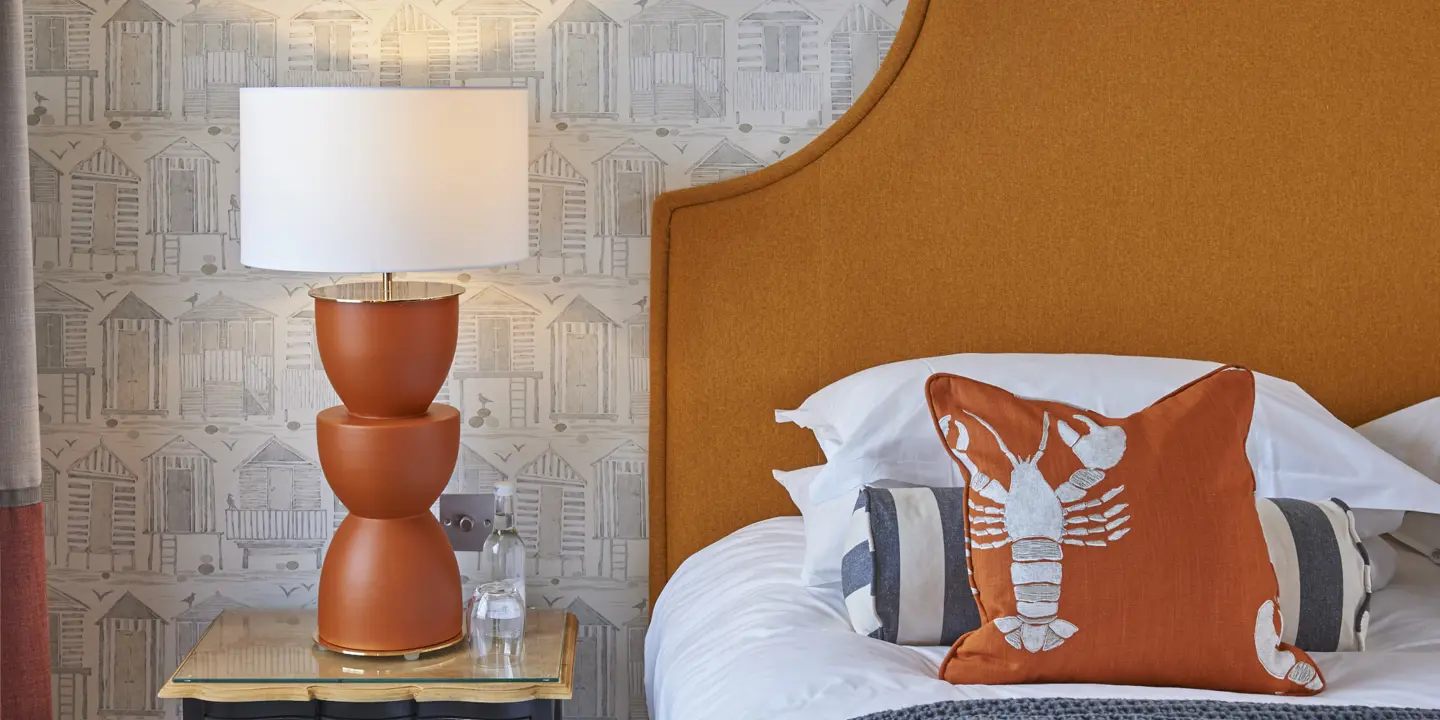 Neatly arranged bedroom with a well-made bed and a lamp.