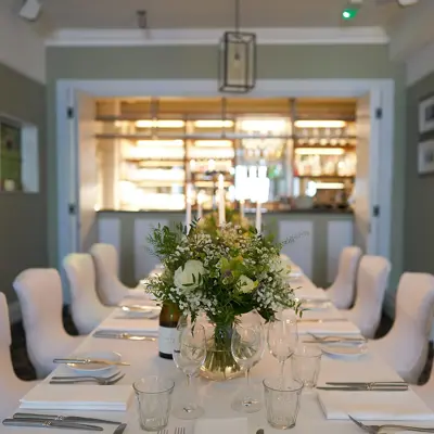 A long table adorned with elegant white chairs and a tastefully arranged vase of flowers.