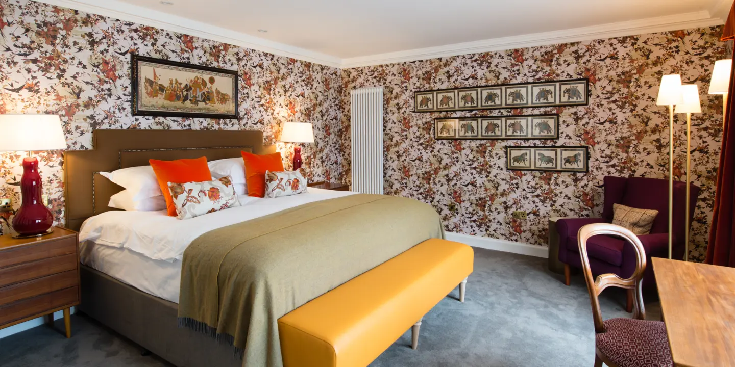 An elegantly furnished bedroom featuring a comfortable bed, a stylish chair, a sleek table, and captivating artwork adorning the walls.