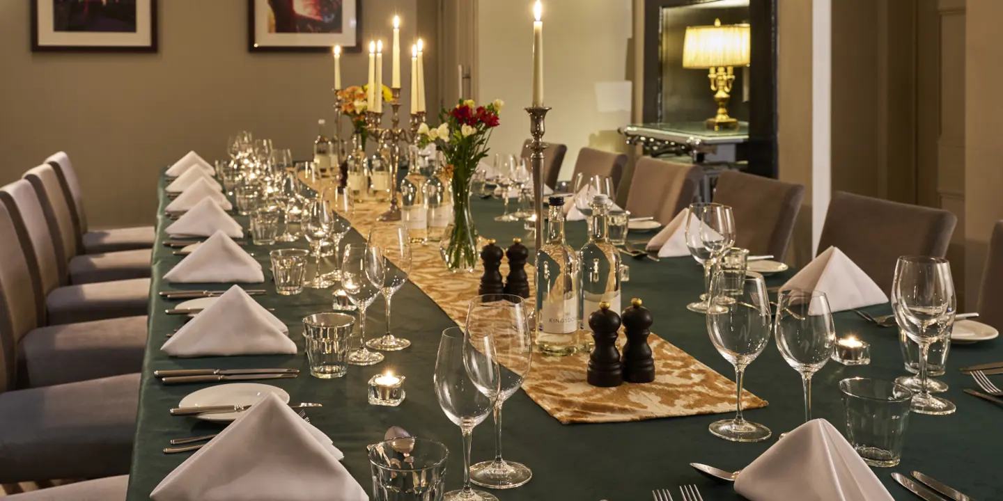 A wooden table adorned with wine glasses and neatly arranged place settings.