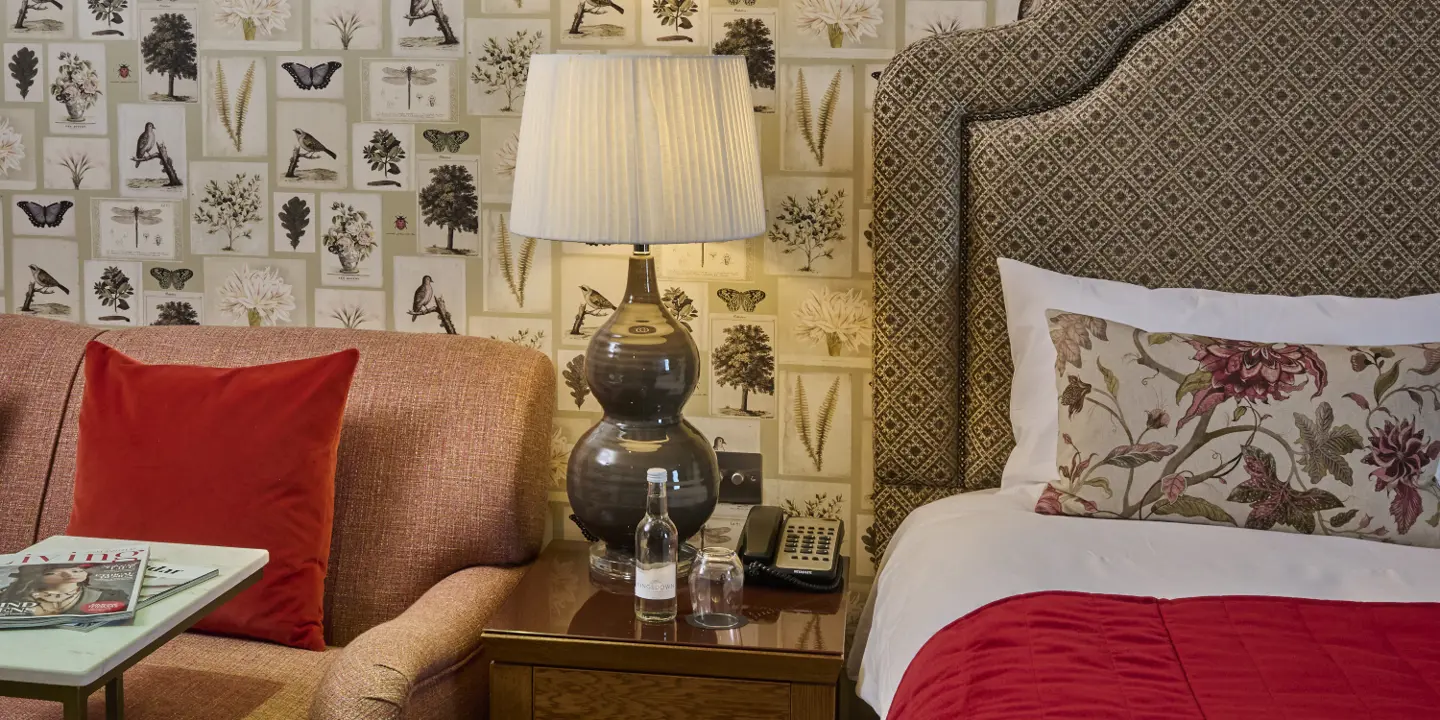 A view of a lamp on a bedside table with a bottle of still water on it