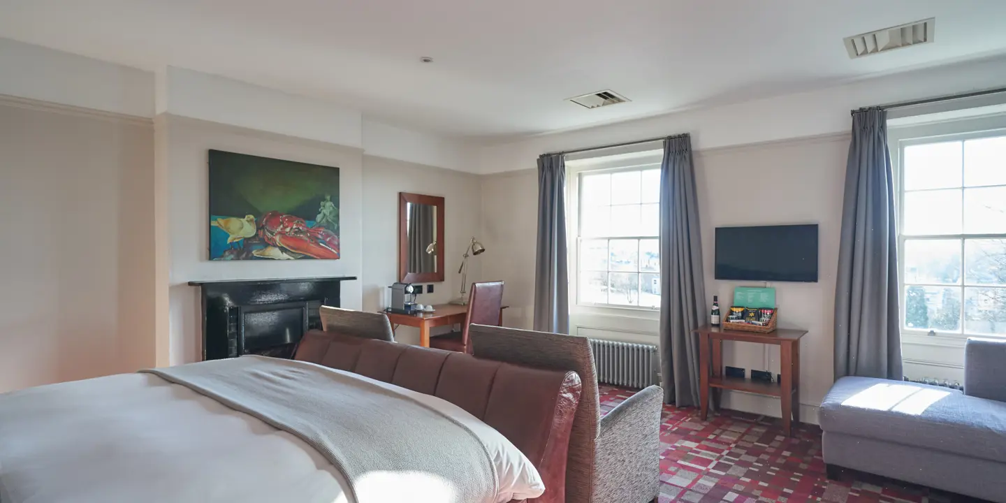 Spacious bedroom featuring a king-sized bed and an elegant fireplace.