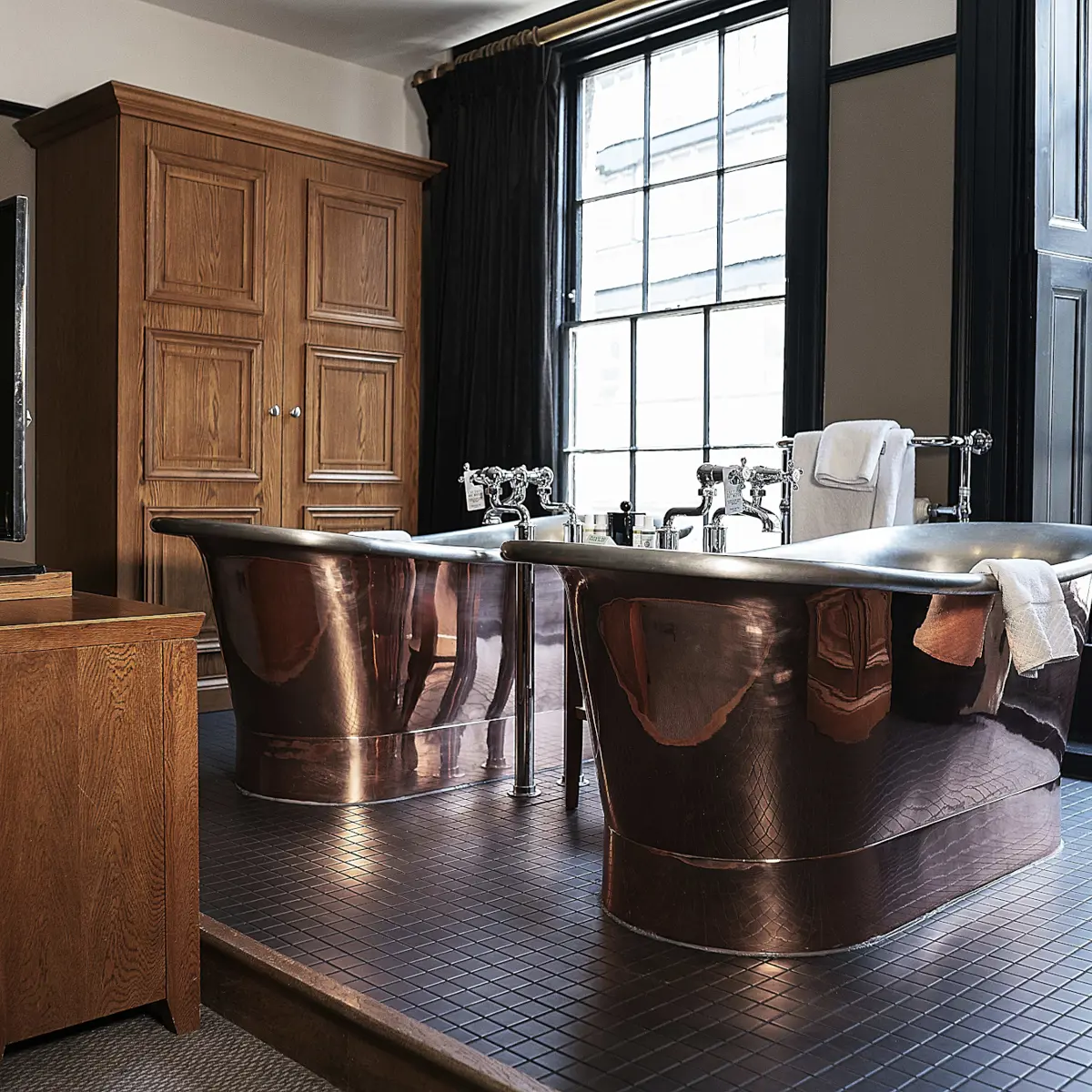 Two large copper bathtubs in a bathroom.