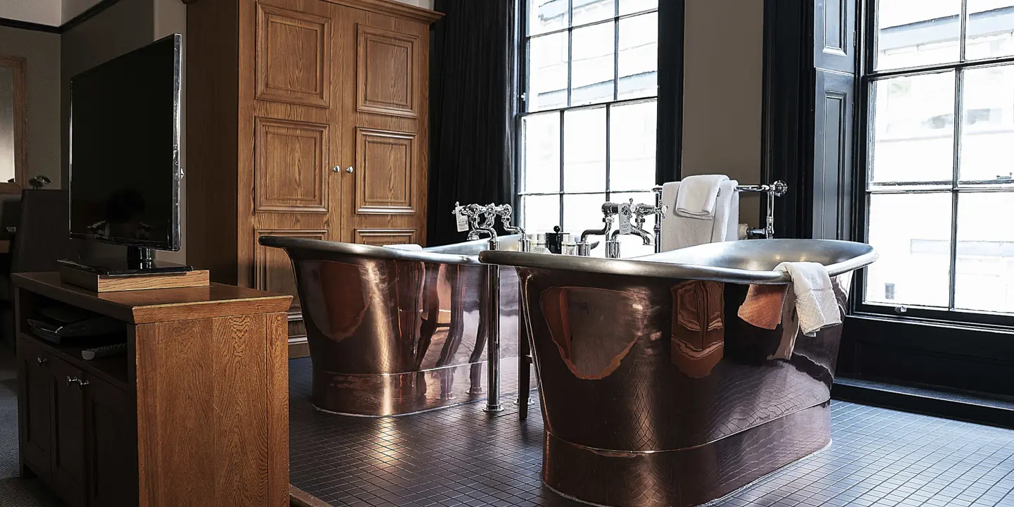 Two large copper bathtubs in a bathroom.