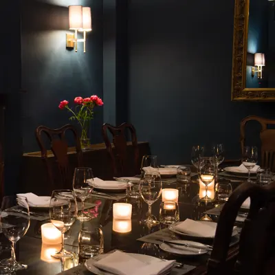 Formally set dining room table for an elegant dinner with lit candles.