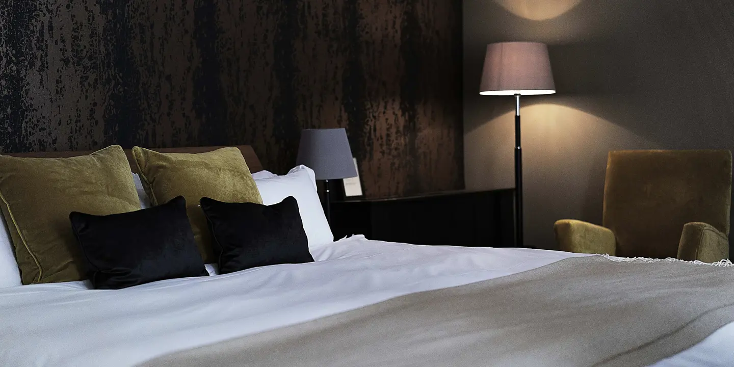 Spacious bedroom featuring a king-sized bed and an elegant chair.