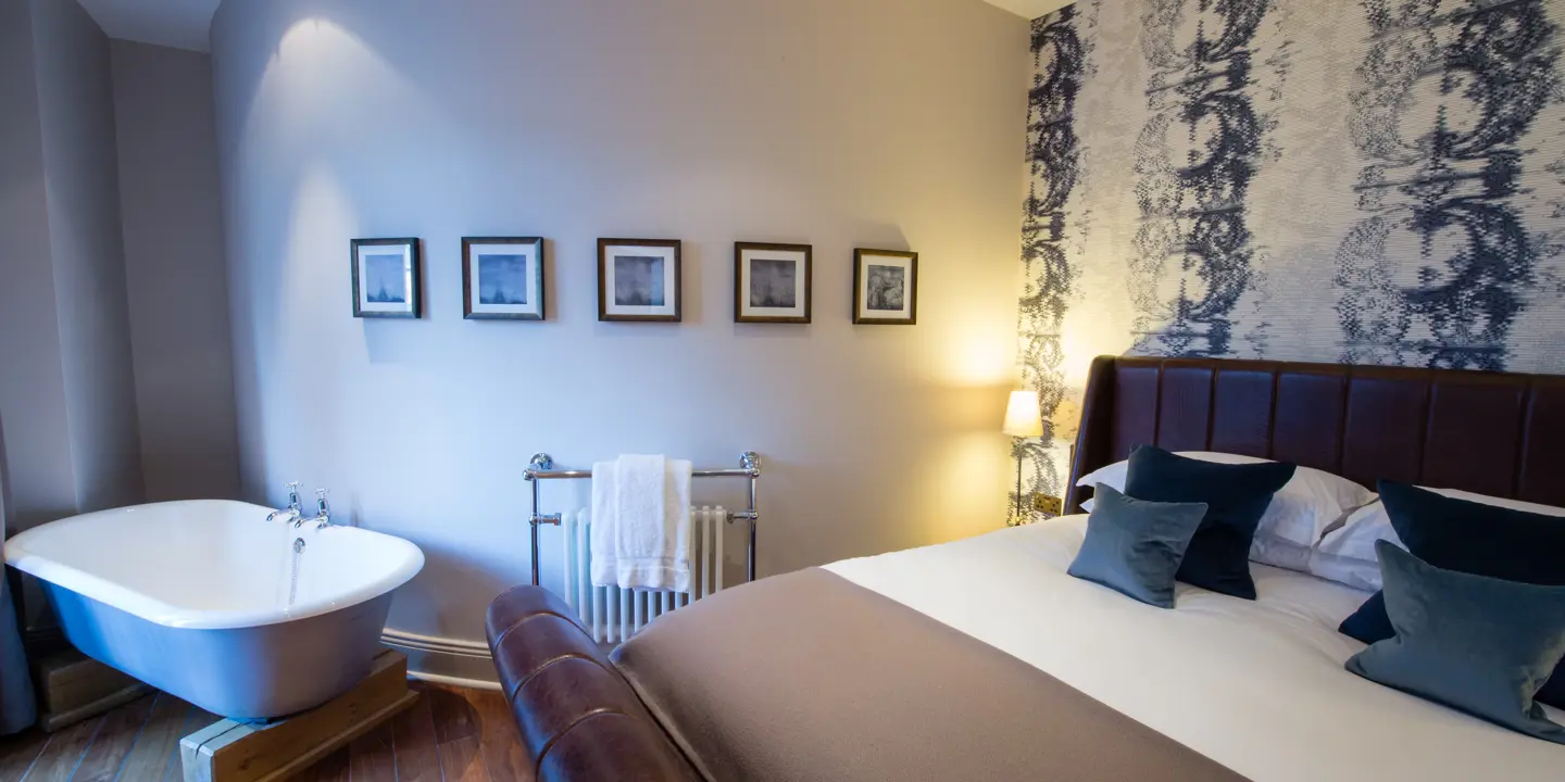 Bed with multiple blue and white pillows and a bath nestled in the corner