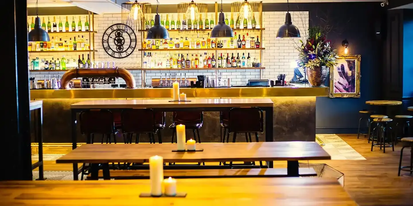 A bar with tables, chairs, and a clock on the wall.