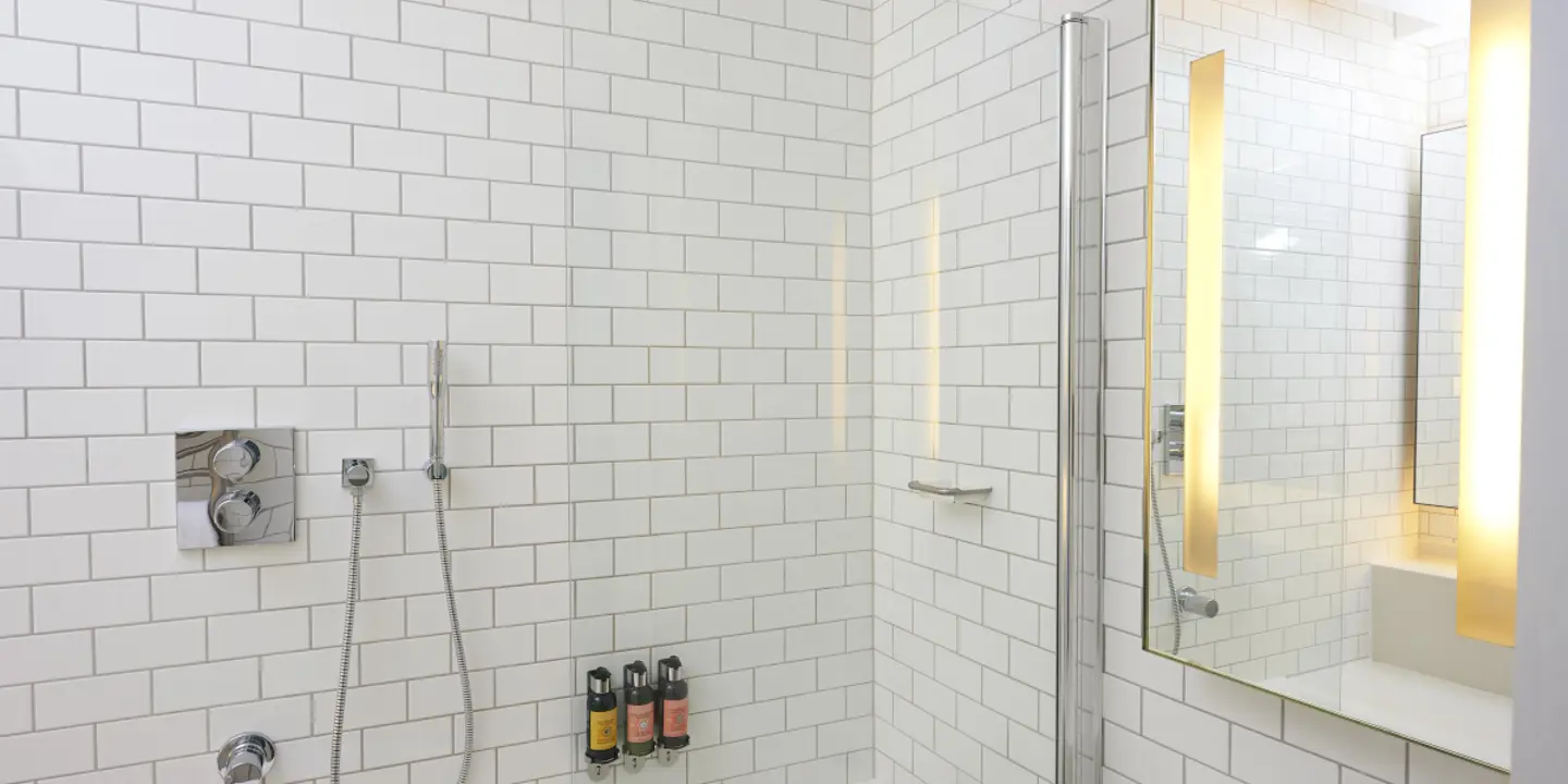 A white-tiled bathroom featuring a shower, sink, and bathtub.