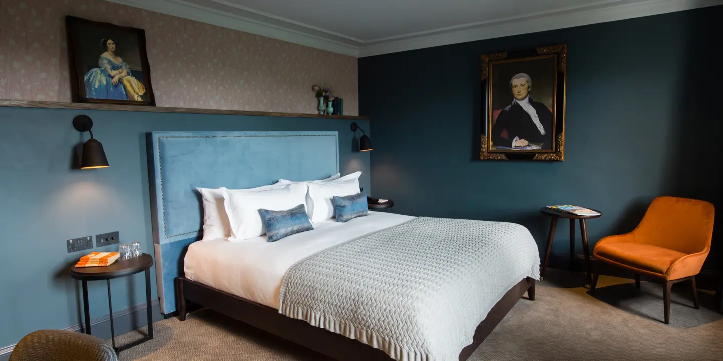 Bedroom featuring a comfortable bed, chair, and wall paintings.