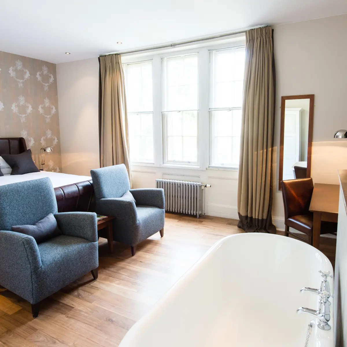 Bedroom featuring a comfortable bed, chair, and bathtub.