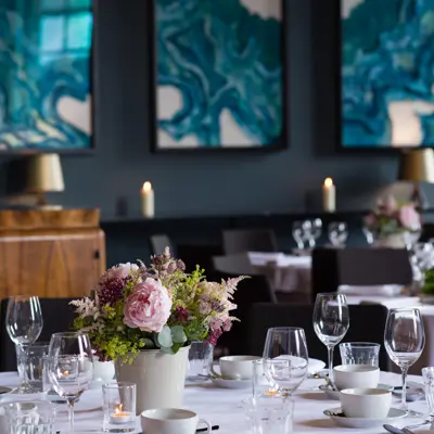 Table arranged with wine glasses, candles and bouquet of flowers.