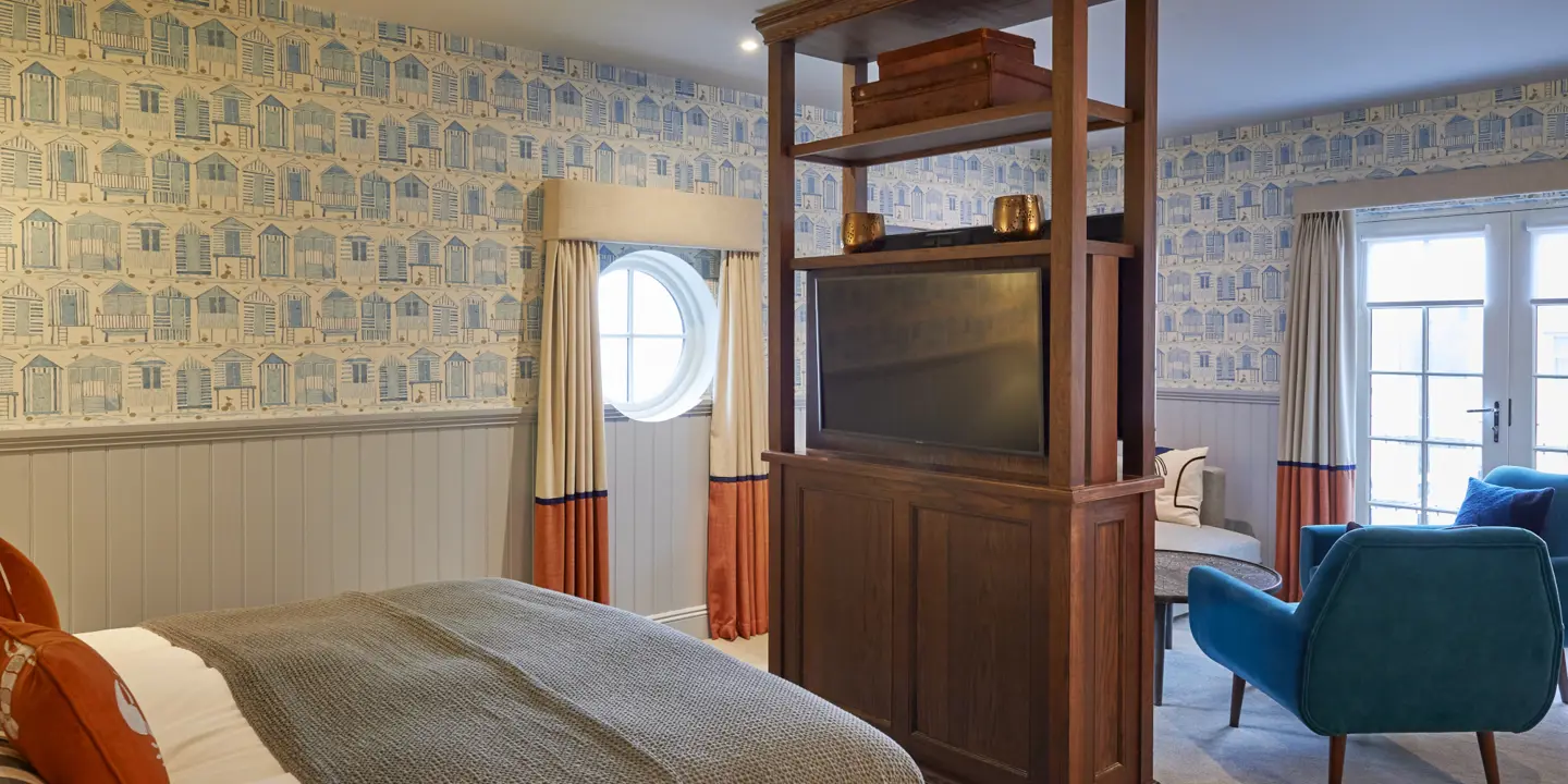 An elegantly furnished bedroom featuring a comfortable bed, a stylish chair, and a modern television.