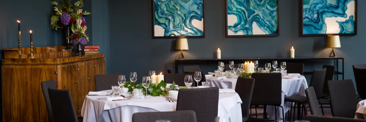 A dining room featuring tables, chairs, and wall paintings.