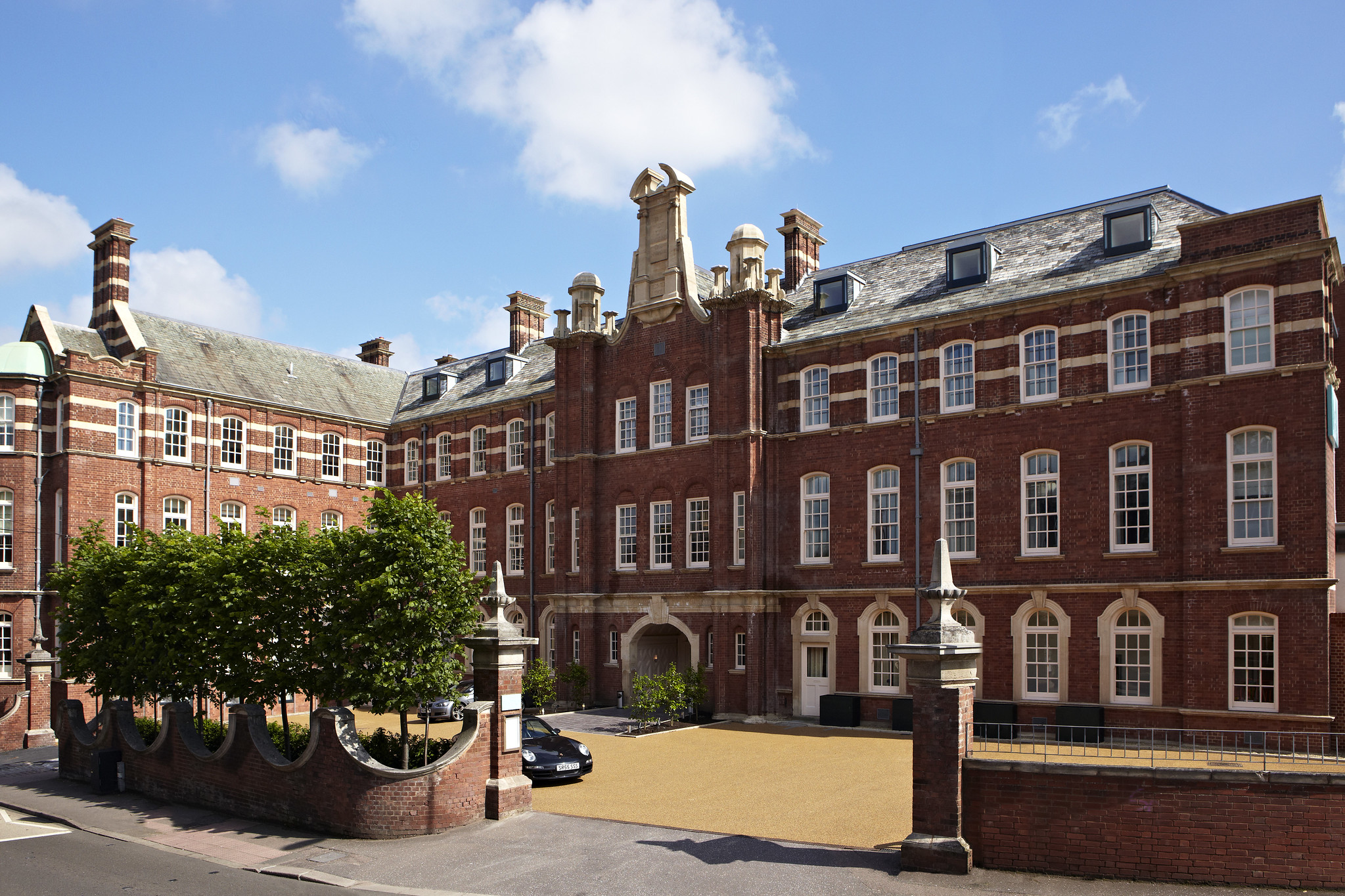 An imposing brick building featuring a brown stoned driveway.